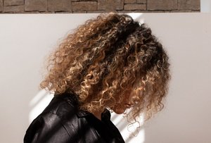 Woman with shoulder-length curly hair with balayage